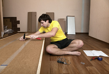 Image showing Young man assembling furniture