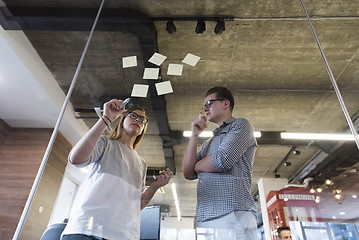 Image showing young couple at modern office interior writing notes on stickers