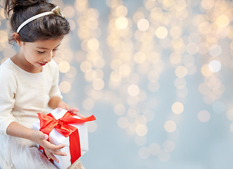 Image showing smiling little girl with gift box over lights