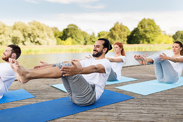 Image showing people making yoga in half-boat pose outdoors