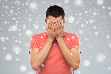 Image showing man covering his face with hands over snow