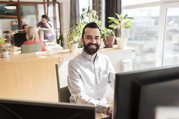 Image showing happy creative male office worker with computer