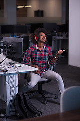 Image showing woman at her workplace in startup business office listening musi