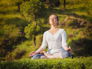 Image showing Young sporty fit woman doing yoga Lotus pose oudoors 