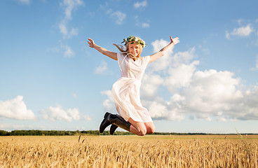 Image showing happy woman in wreath jumping on cereal field