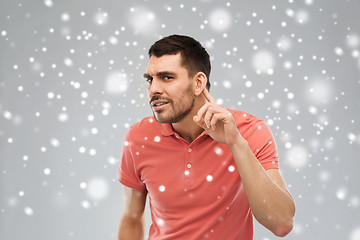 Image showing man having hearing problem listening to something