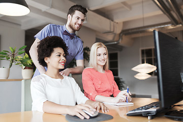 Image showing happy creative team with computer in office