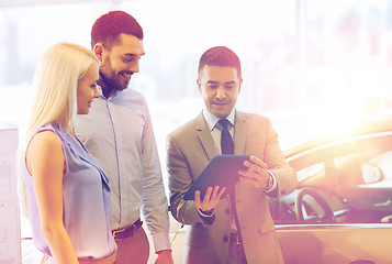 Image showing happy couple with car dealer in auto show or salon