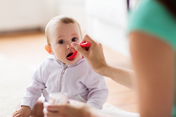 Image showing mother with spoon feeding little baby at home