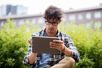 Image showing man in glasses with tablet pc on city steet