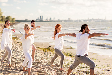 Image showing people making yoga in warrior pose on beach