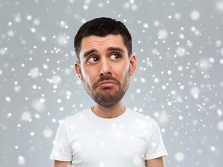 Image showing unhappy young man over snow background