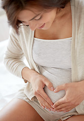 Image showing close up of pregnant woman making heart gesture