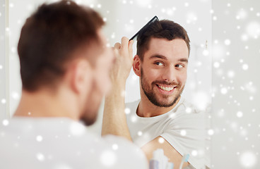 Image showing happy man brushing hair with comb at bathroom