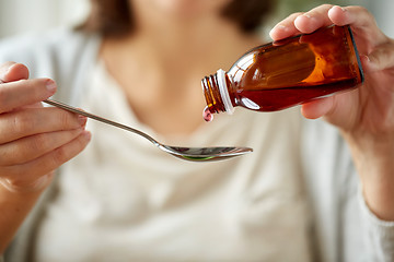 Image showing woman pouring medication from bottle to spoon