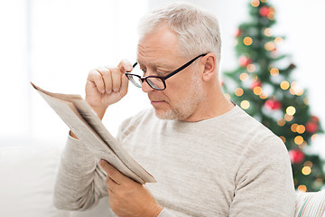 Image showing senior man in glasses reading newspaper at home