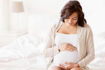 Image showing happy pregnant woman sitting on bed at home