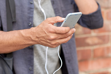 Image showing close up of man with smartphone and earphones wire