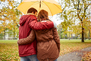 Image showing happy couple with umbrella walking in autumn park