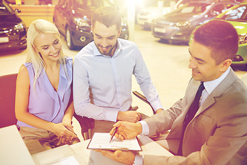 Image showing happy couple with car dealer in auto show or salon