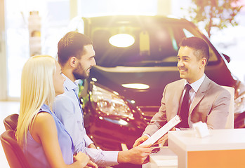 Image showing happy couple with car dealer in auto show or salon