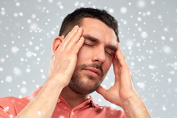 Image showing unhappy man suffering from head ache over snow