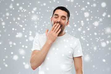 Image showing tired yawning man over snow