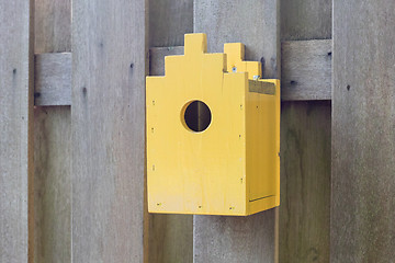 Image showing Yellow birdhouse on a wooden fence