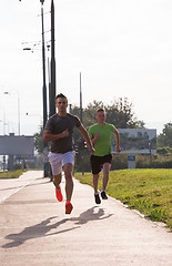 Image showing Two young men jogging through the city