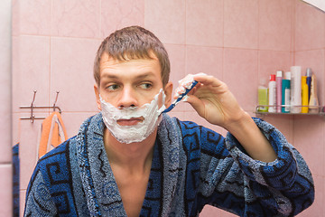 Image showing Young man shaves the stubble on his cheek