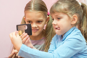 Image showing Two children considered a coin through a magnifying glass