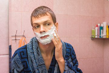 Image showing The young man gets shaving foam on face