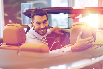 Image showing happy man sitting in car at auto show or salon