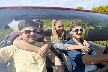 Image showing happy friends driving in cabriolet car outdoors