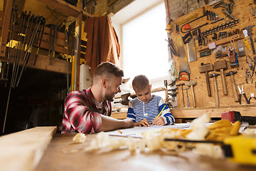 Image showing happy father and son with blueprint at workshop