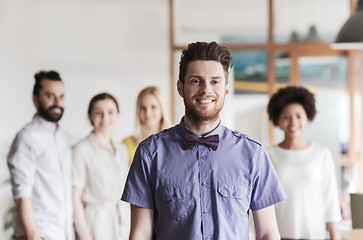 Image showing happy young man over creative team in office