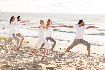 Image showing people making yoga in warrior pose on beach