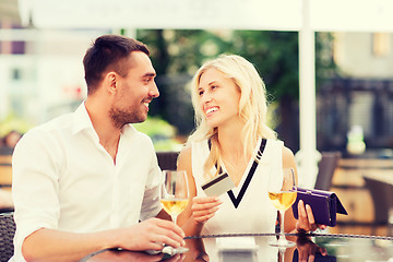 Image showing happy couple with bank card and bill at restaurant