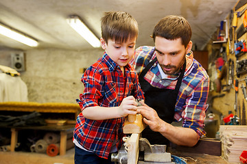 Image showing father and son with plane shaving wood at workshop