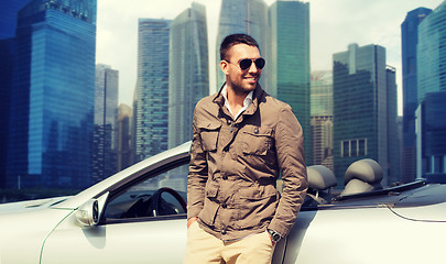 Image showing happy man near cabriolet car over city background