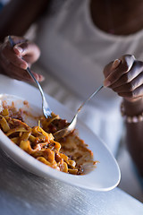 Image showing a young African American woman eating pasta