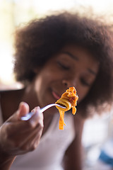 Image showing a young African American woman eating pasta