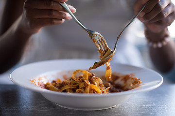 Image showing a young African American woman eating pasta