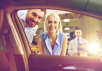 Image showing happy couple with car dealer in auto show or salon