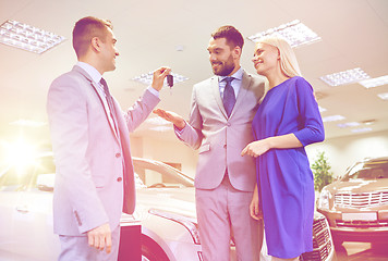 Image showing happy couple with car dealer in auto show or salon