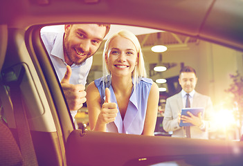 Image showing happy couple with car dealer in auto show or salon