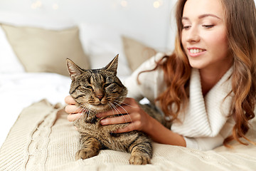 Image showing happy young woman with cat lying in bed at home