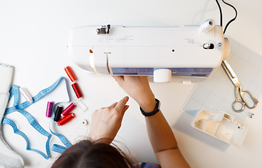 Image showing Girl sets up sewing machine