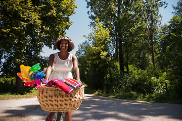 Image showing pretty young african american woman riding a bike in forest