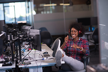 Image showing woman at her workplace in startup business office listening musi